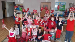 Dzieci ubrane na czerwono machaja balonami serduszkami