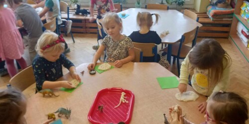 zabawy z dinozaurami dzieci przy stolikach tworzą skamieliny