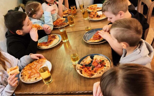 Dzieci zajadają pizzę i piją sok