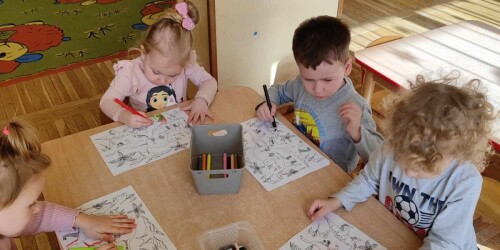 Dzieci kolorują kolorowanki z dinozaurami