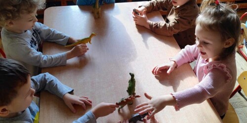 Dzieci przy stolikach bawią sie dinozaurami