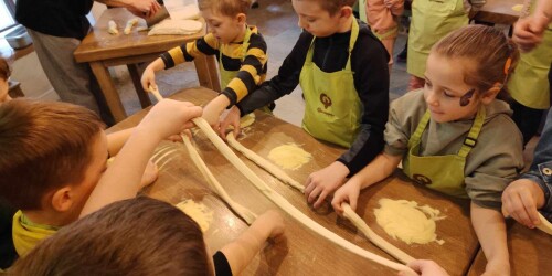 Dzieci bawią się ciastem do pizzy robią wałeczki