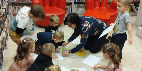 Dzieci z panią bibliotekarką malują na podłodze