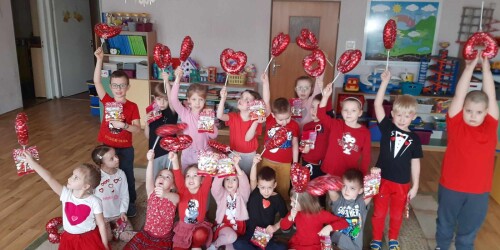 Dzieci ubrane na czerwono machaja balonami serduszkami