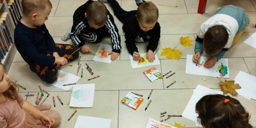 Dzieci na podłodze malują kredkami obrazki